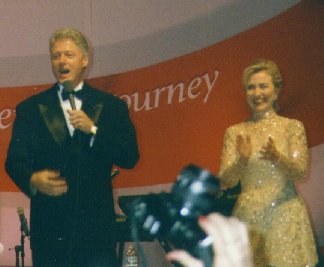 Bill with microphone in hand and Hillary applauding.